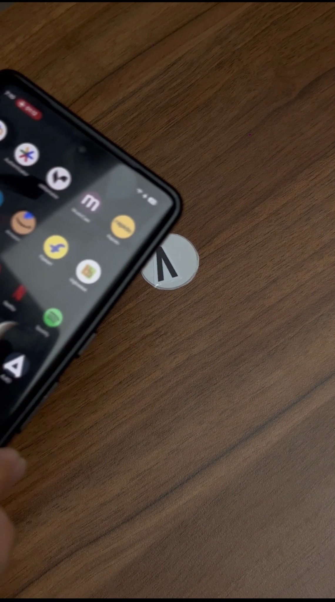 Phone approaching an NFC sticker on a wooden tabletop to open lighting controls